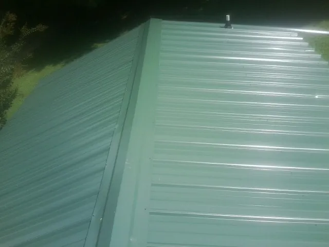 New green metal panels meeting at the ridge of a roof — Flat Roof Repair work by our crew in Venus