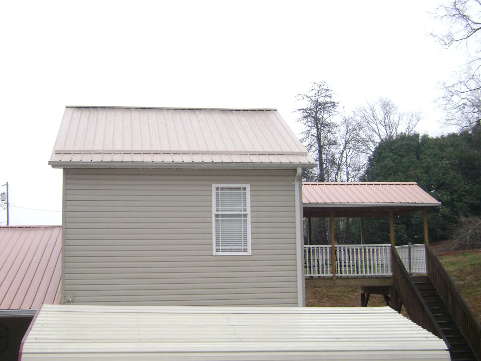 Tan metal roofs on a two story addition and attached porch, from a Roof Replacement job in Venus